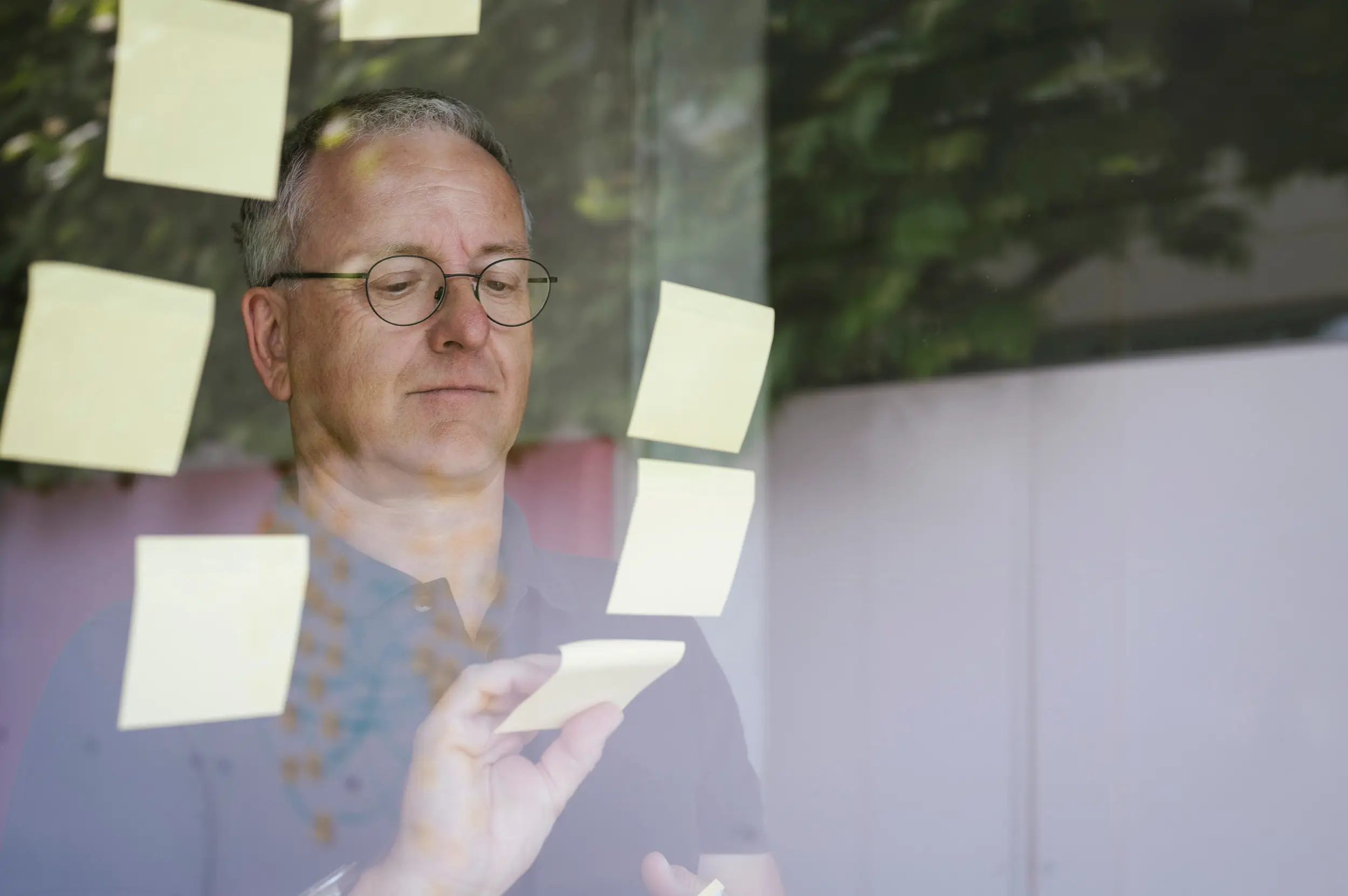 Richard Zauner sortiert Post-its an einer Glasscheibe bei der Organisationsentwicklung
